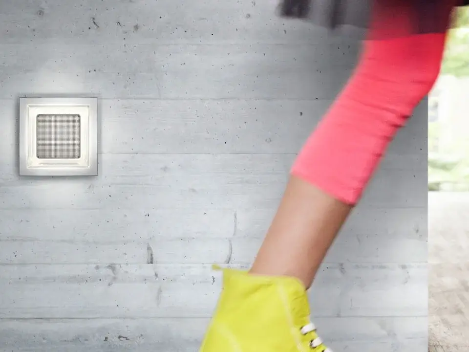 Bewegte Person in hellen Schuhen neben aufhellenden Wandlampen.