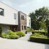 Moderner Wohnhaus mit einer Kombination aus Putz- und Holzverkleidung, umgeben von gepflegtem Garten und Weg.