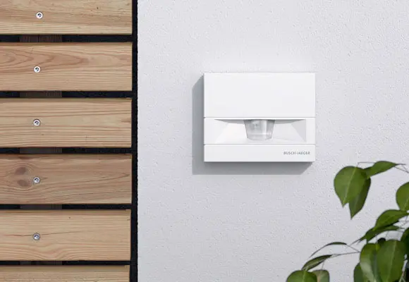 Bewegungsmelder in weißer Wandmontage neben Holzleisten.