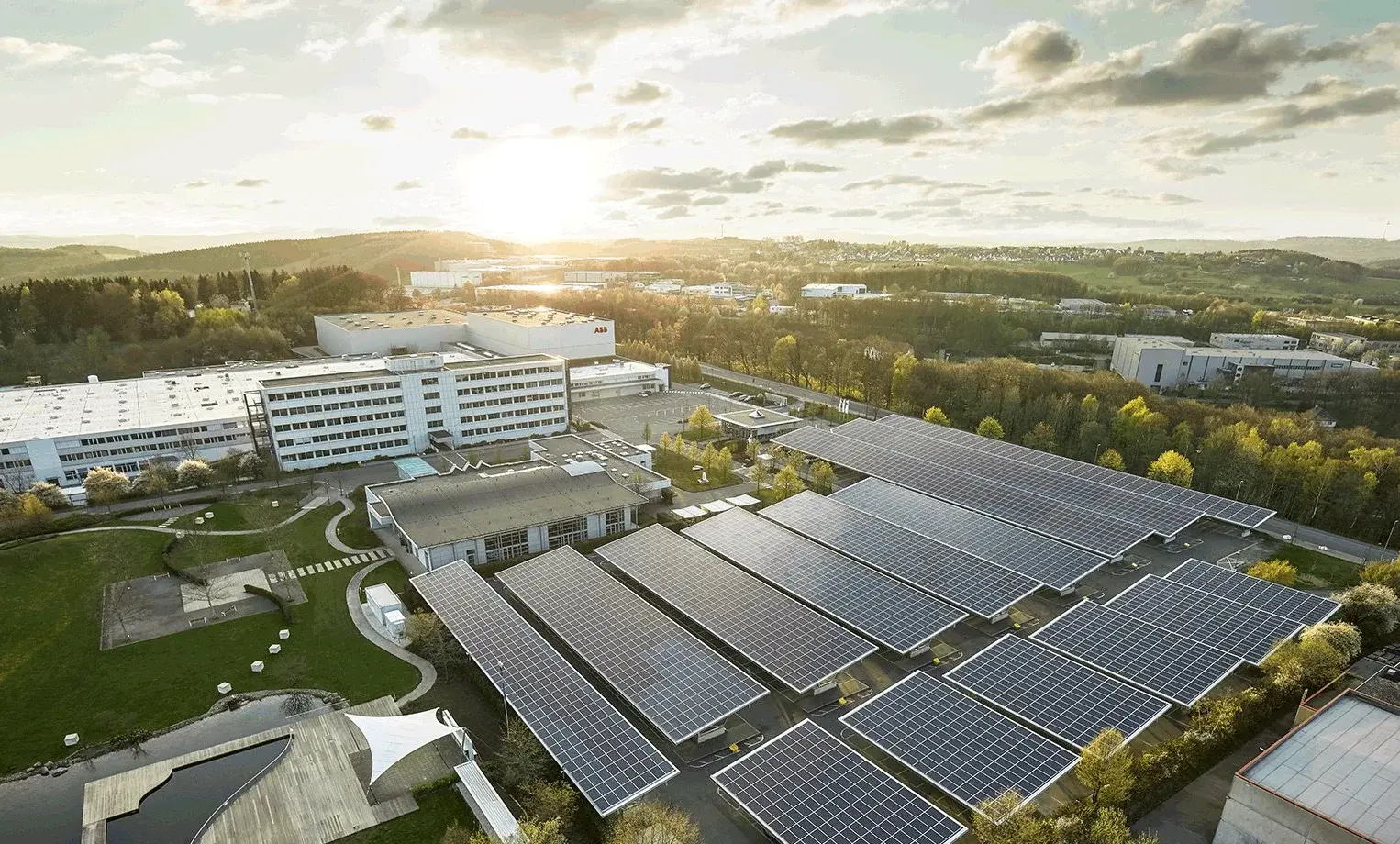 Luftaufnahme eines Gebäudes mit Solarpanels auf dem Gelände und umgebenden Grünflächen.