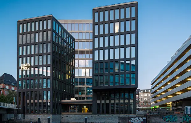 Moderne Bürogebäude mit großflächigen Fenstern und klaren Linien, in einer urbanen Umgebung.