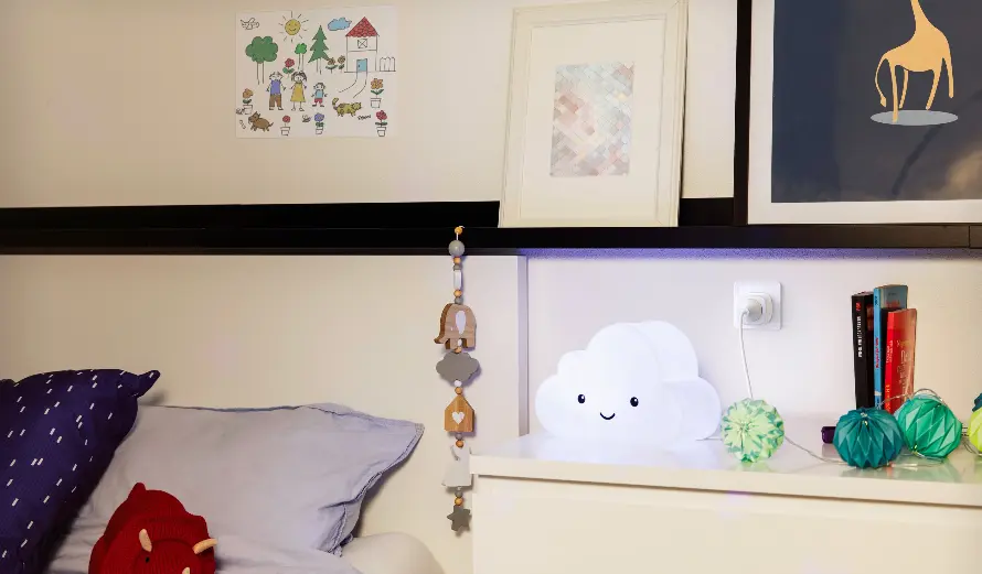 Ein Nachttisch mit einer Wolkenlampe, einem Buch, Dekorationselementen und einem Schlafzimmer mit einem Kissen.