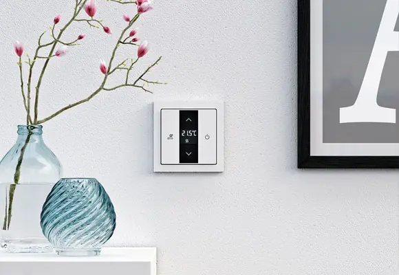 Thermostat an der Wand mit Temperaturanzeige und Bedienelementen für die Temperatureinstellung.